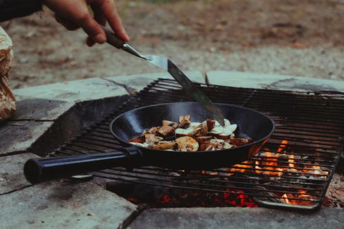 a person cooking food in a pan on a grill at Attla Skogsby in MÃ¥nsarp