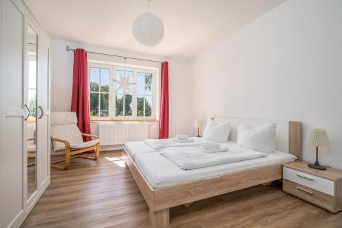 a white bedroom with a large bed and a window at FeWo Haus kleine Müritz in Rechlin