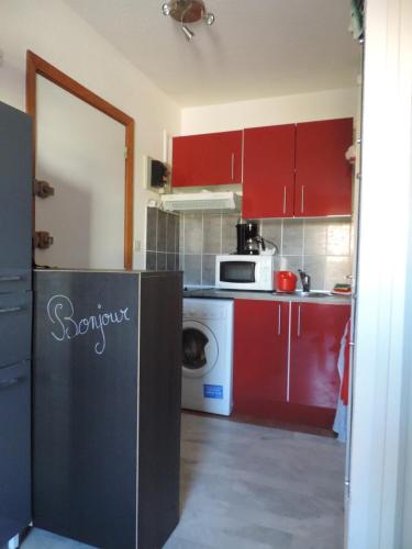 une cuisine avec des armoires rouges et un appareil blanc dans l'établissement 5038 Agde Marine C12, au Cap d'Agde