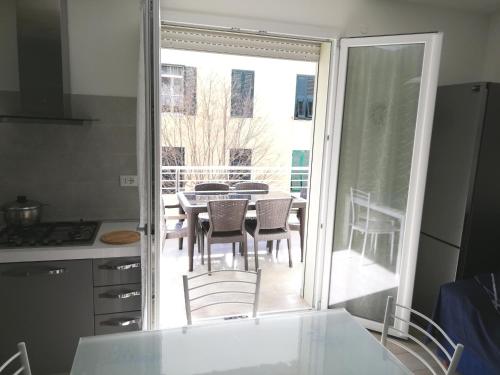cocina con mesa y sillas y balcón en Nuovissimo appartamento con terrazza, en Alghero