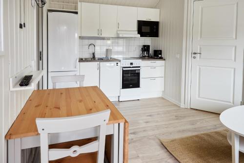 a kitchen with a wooden table and white cabinets at Lagunen Cottages and Hostel in Strömstad