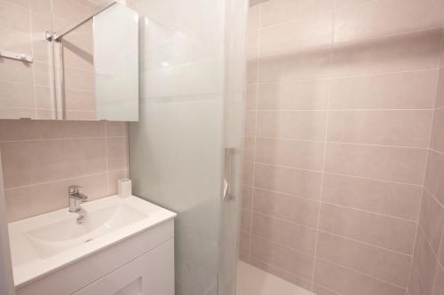 une salle de bain blanche avec un lavabo et un miroir dans l'établissement * Hossegor * Rénové * Piscine * Parking * Famille, à Soorts-Hossegor