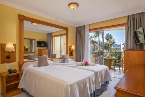 a hotel room with two beds and a balcony at GF Noelia in Puerto de la Cruz