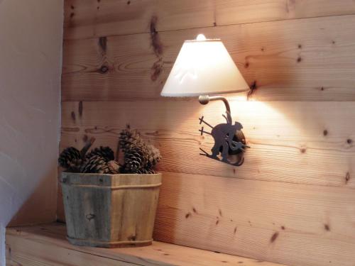 a lamp on a wall next to a bucket of pine cones at Le Dahu in Chamonix-Mont-Blanc