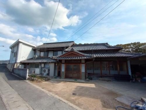 an asian house with a roof on a street at ゲストハウス　tonari in Inokuchi