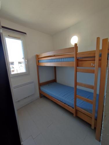 une petite chambre avec deux lits superposés et une fenêtre dans l'établissement SOPRALAND Joli T2 piscine proche plage Richelieu Cap d'Agde, au Cap d'Agde
