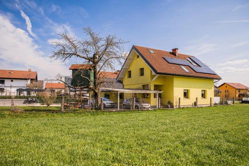a yellow house with a red roof in a field at Mountain View Apartment with Sauna in Cerklje na Gorenjskem