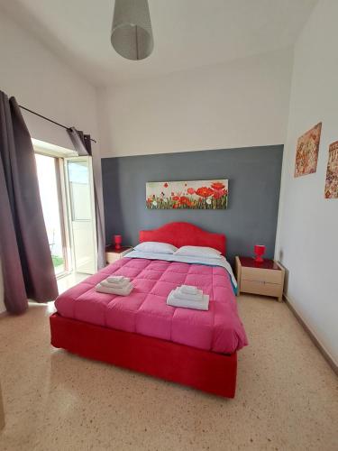 um quarto com uma cama vermelha e um cobertor rosa em La Casa del Borgo em Lecce