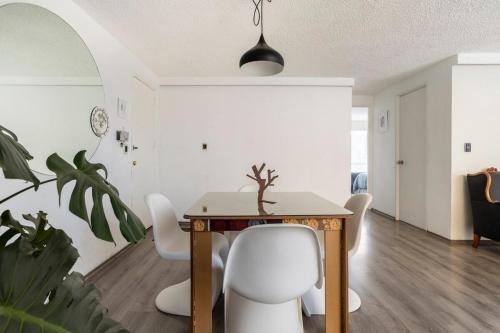 a dining room with a table and white chairs at Increible departamento en la del valle in Mexico City