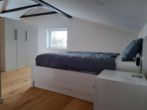 a white bedroom with a bed and a window at GAMSI Apartment in Ljubljana