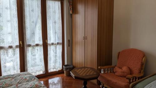 a bedroom with a chair and a window at La Margherita di Teriasca in Teriasca