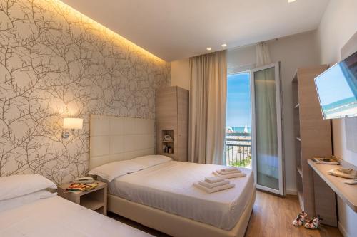 a hotel room with two beds and a television at Hb Hotels Orchidea Blu in Rimini