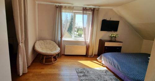 um quarto com uma cama, uma cadeira e uma janela em Svečių namai Kamile em Siauliai