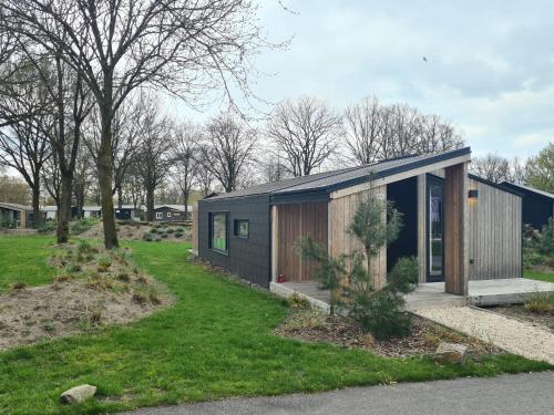 a small black house on a grass field at Chalet Panorama near Efteling - with garden and swimmingpool Europarcs in Kaatsheuvel