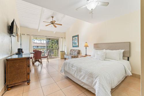 a bedroom with a bed and a desk and a television at Kihei Bay Surf B212 in Kihei