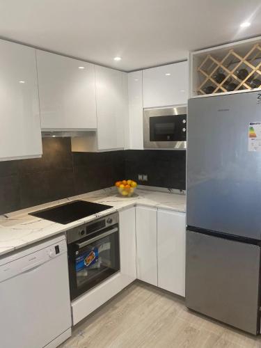 a kitchen with white cabinets and a stove and a refrigerator at Beautiful refurbished apartment Duquesa port in Casares