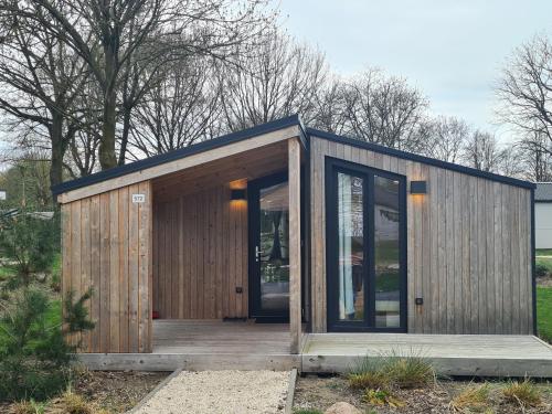 a small wooden building with a large glass door at Chalet Panorama near Efteling - with garden and swimmingpool Europarcs in Kaatsheuvel
