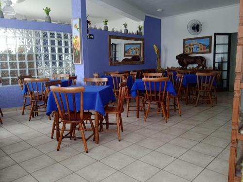 a dining room with blue tables and wooden chairs at Pousada Sereia Jofisa in Itanhaém