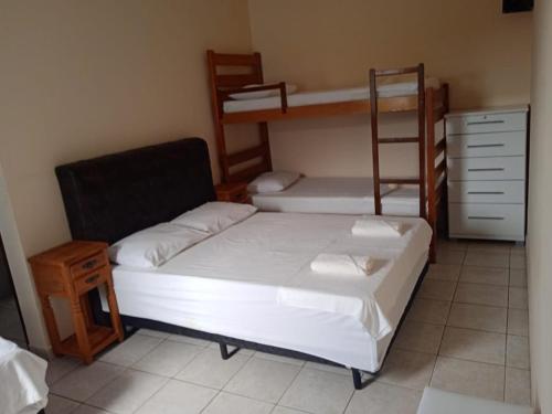 a bedroom with two bunk beds and a chair at Pousada Sereia Jofisa in Itanhaém