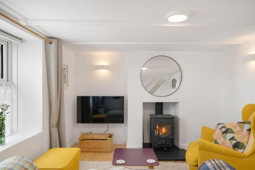 彭贊斯的住宿－Copper Bal Cottage，客厅设有黄色椅子和壁炉
