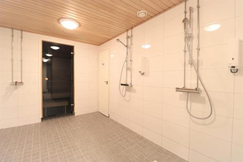 a bathroom with white tiled walls and a shower at Forenom Aparthotel Helsinki Herttoniemi in Helsinki