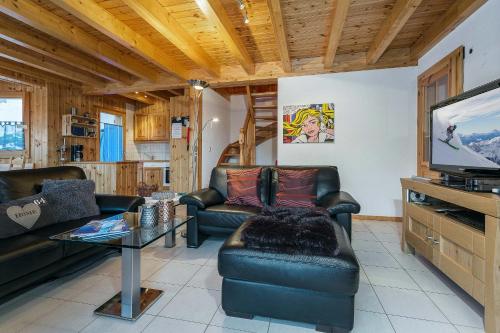 a living room with leather furniture and a flat screen tv at Chalet Colonia in La Tzoumaz