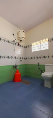 a bathroom with a toilet and a light on the wall at The Coorg Heaven in Madikeri