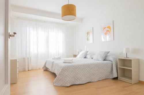 ein weißes Schlafzimmer mit einem Bett und einem Fenster in der Unterkunft Apartamento Tomillo I in Candeleda
