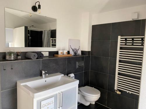 La salle de bains est pourvue d'un lavabo blanc et de toilettes. dans l'établissement Moderne 70 qm Ferienwohnung in Waldrandlage, à Eppelborn