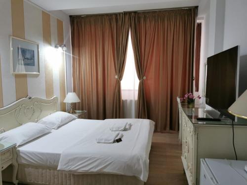 a bedroom with a white bed and a television at Nevis Fundeni in Bucharest