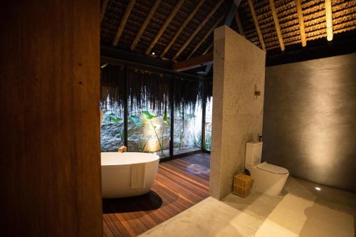 baño con bañera, aseo y ventana en Paru Boutique Hotel, en São Miguel dos Milagres