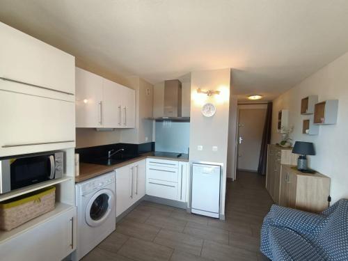 uma cozinha com armários brancos e uma máquina de lavar e secar roupa em T2 vue Mer - St Pierre la Mer 2PLM67 em Saint Pierre La Mer