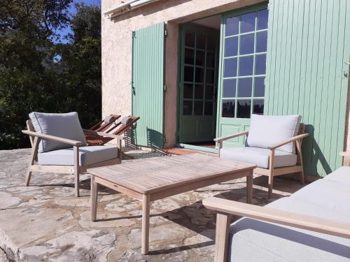 grupa krzeseł i drewniany stół na patio w obiekcie Villa VUE MER plage de La FOSSETTE 5mn à pied Proche du Centre w mieście Le Lavandou