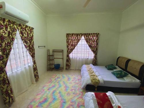 a bedroom with two beds and two windows with curtains at Batu Pahat Qastina Gunong Soga Homestay in Batu Pahat