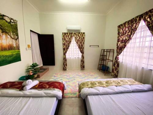 two beds in a room with two windows at Batu Pahat Hill View Homestay in Batu Pahat