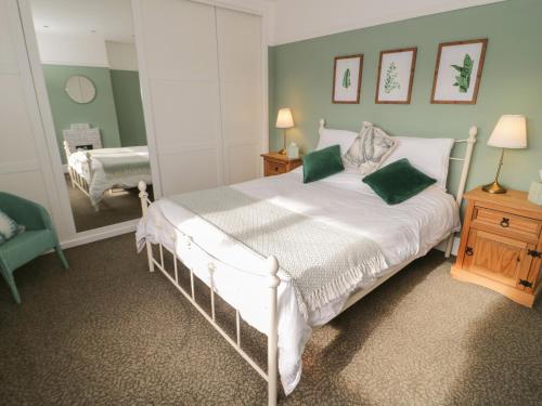 a bedroom with a large white bed with green walls at Dulas in Llandudno Junction