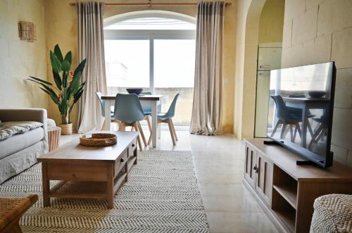 a living room with a couch and a tv and a table at Ogygia Suites Gozo in Għarb