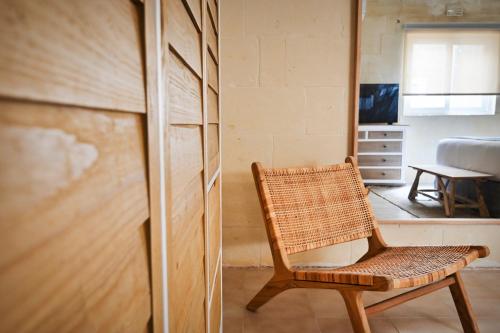 a wicker chair sitting in a room with a closet at Ogygia Suites Gozo in Għarb