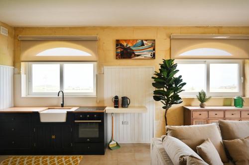 a kitchen with a sink and a couch and two windows at Ogygia Suites Gozo in Għarb