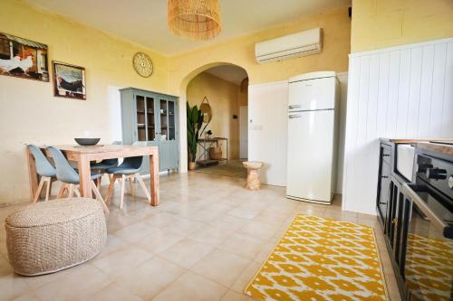 a kitchen and dining room with a table and refrigerator at Ogygia Suites Gozo in Għarb