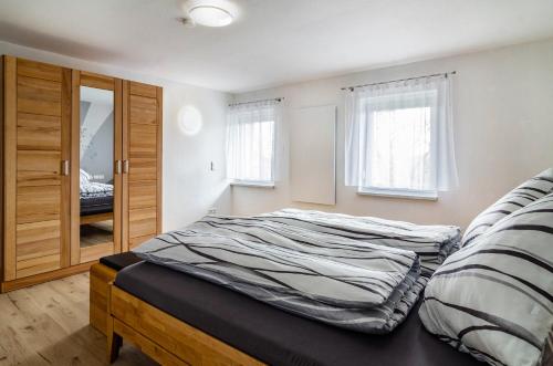 a bedroom with a bed and a closet and windows at Lidobo 01 in Herdwangen-Schönach