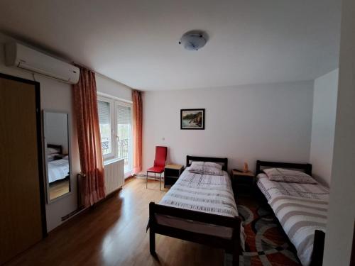 a bedroom with two beds and a red chair at Privatni smještaj Tolić in Ladimirevci