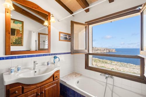 łazienka z umywalką, wanną i oknem w obiekcie Binizzy w mieście Cala Morell