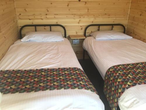 drie bedden in een kamer met houten wanden bij Beacon House Bunks in Bridlington