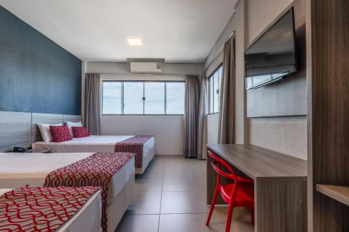 a hotel room with two beds and a desk at 103 Hotel & Flats in Palmas