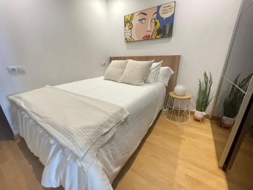 a bedroom with a bed with white sheets and a picture on the wall at Loft en el mercado del Fontan in Oviedo