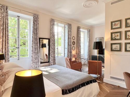 a bedroom with a bed and two windows at Le Clos Saluces in Avignon