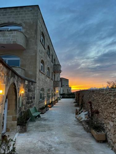 a stone building with a pathway next to a stone wall at Ogygia Suites Gozo in Għarb