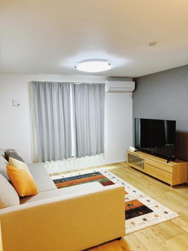 a living room with a couch and a flat screen tv at 成田羽田空港直行 skytree 上野 asakusa 銀座直行 駅から徒歩8分新築戸建 駐車場付いてない in Tokyo