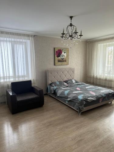 a bedroom with a bed and a chair and a chandelier at ВІП квартира в новобудові в центрі міста in Rivne